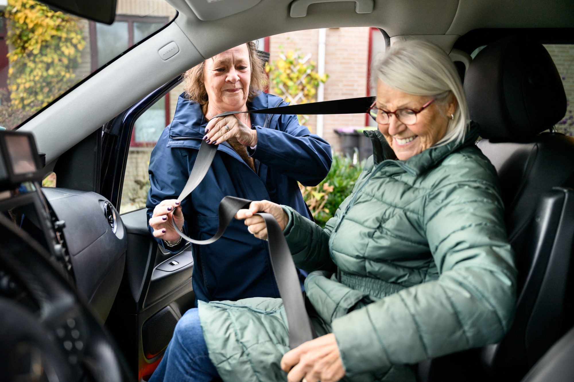 chauffeur helpt oudere dame met gordel