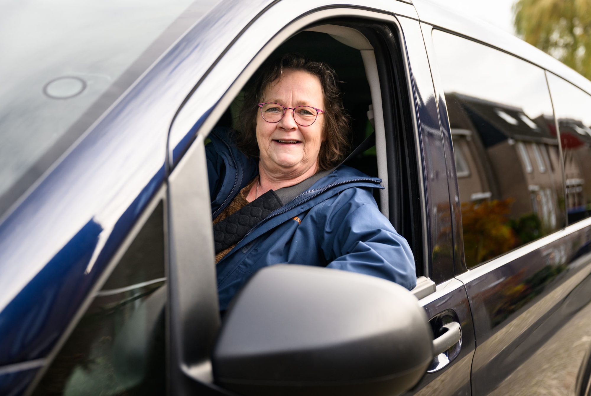 vrouwelijke chauffeur kijkt uit raam en lacht